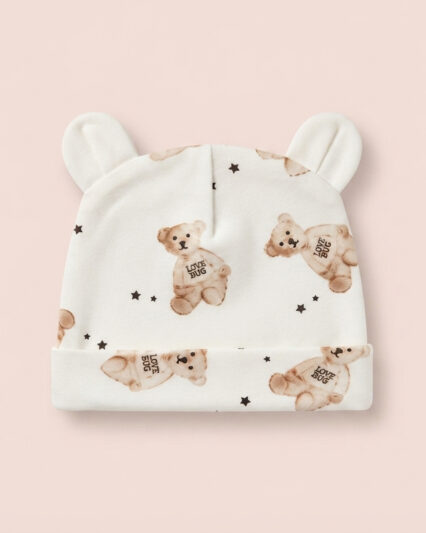 Cream baby beanie with bear ears and a watercolour teddy bear print on a soft pink background